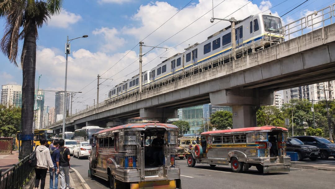 LRT-1 train, jeepneys and city traffic in urban Pasay