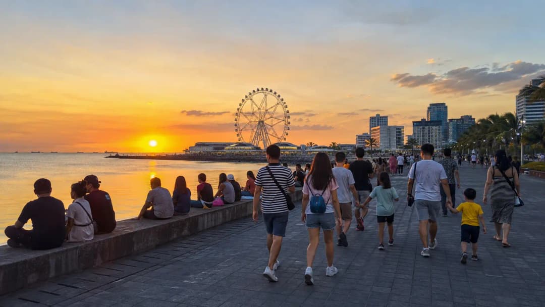 Travelers walking beside Manila Bay at sunset near the MOA observation wheel