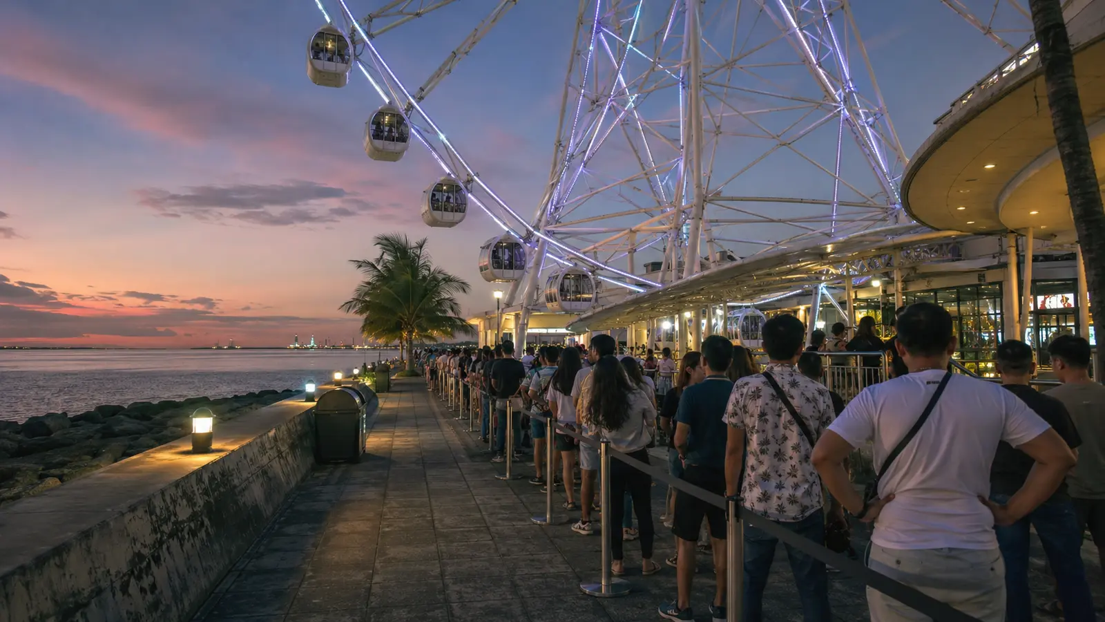 Large observation wheel glowing beside Manila Bay at dusk