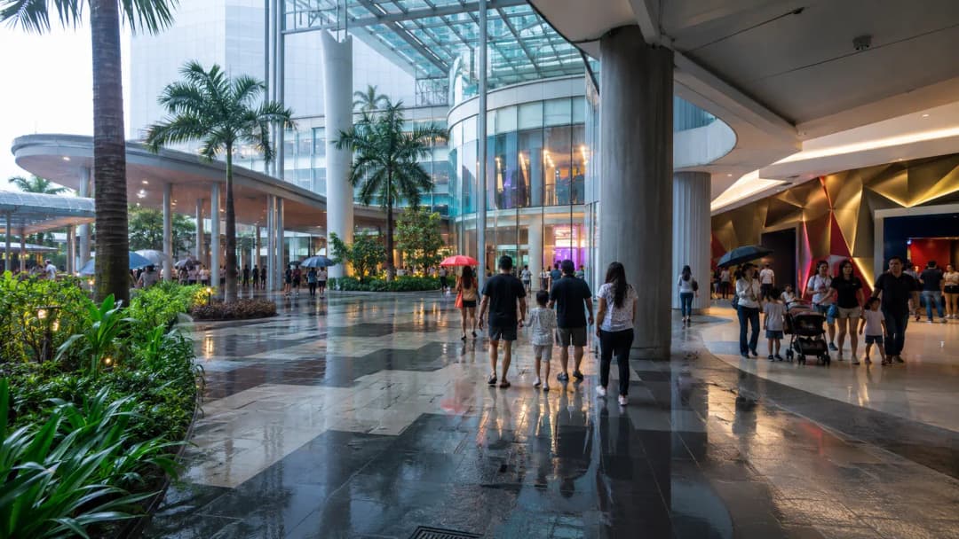 Visitors entering a modern Pasay mall under covered walkways during tropical rain