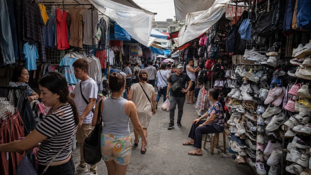 Local shoppers browsing clothing and accessories in a busy Baclaran market aisle