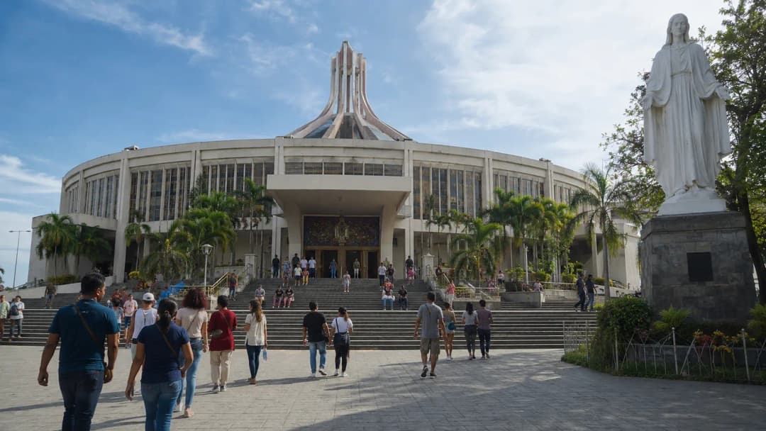 Respectful visitors entering a large Catholic shrine in Baclaran on a bright morning