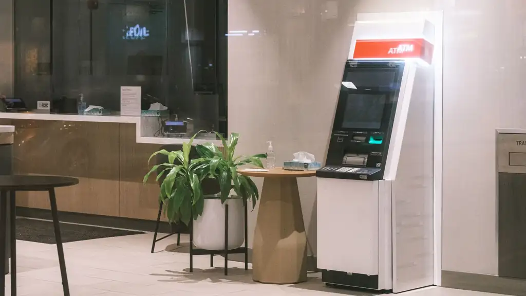 Traveler using a secure ATM beside a bright Manila shopping promenade with a wallet and pesos