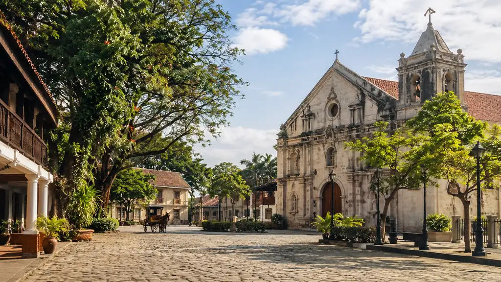Cavite heritage church plaza with tropical trees and traditional architecture on a sunny morning