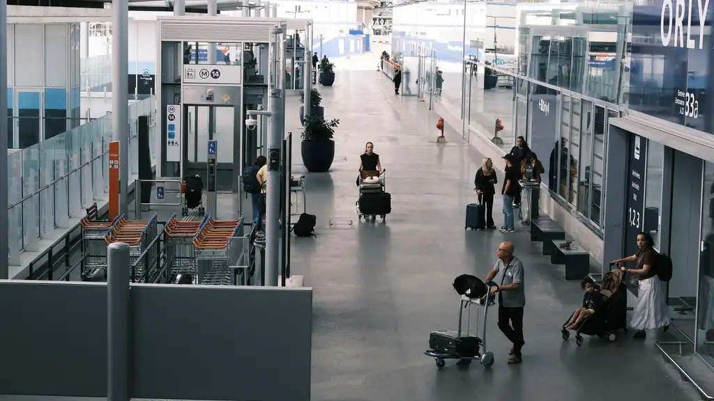 Travelers with large suitcases and sports equipment at a clean Pasay transport terminal curb