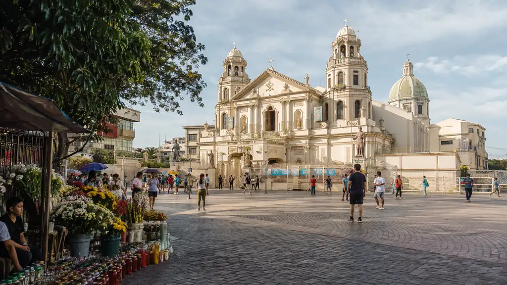 Historic Quiapo Church plaza in Manila with flower vendors and visitors in soft morning light