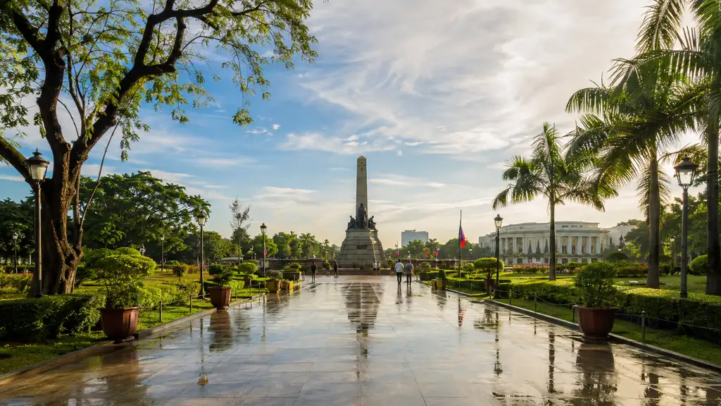 Rizal Park landscaped promenade after rain with monument and Manila architecture in morning light